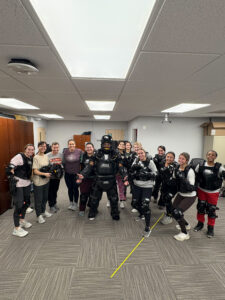 Students in a self-defense class pose in a defensive stance with their instructor.