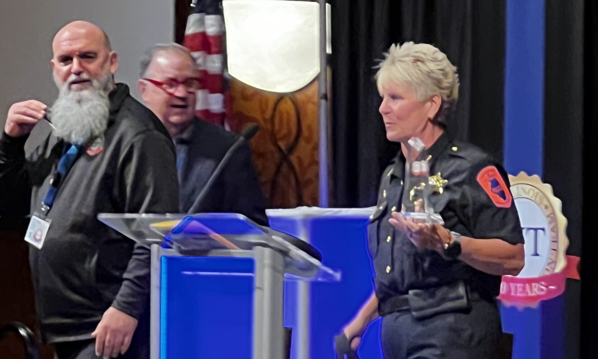 Chief Cary in a UIPD uniform holds a glass award while standing at a lectern.