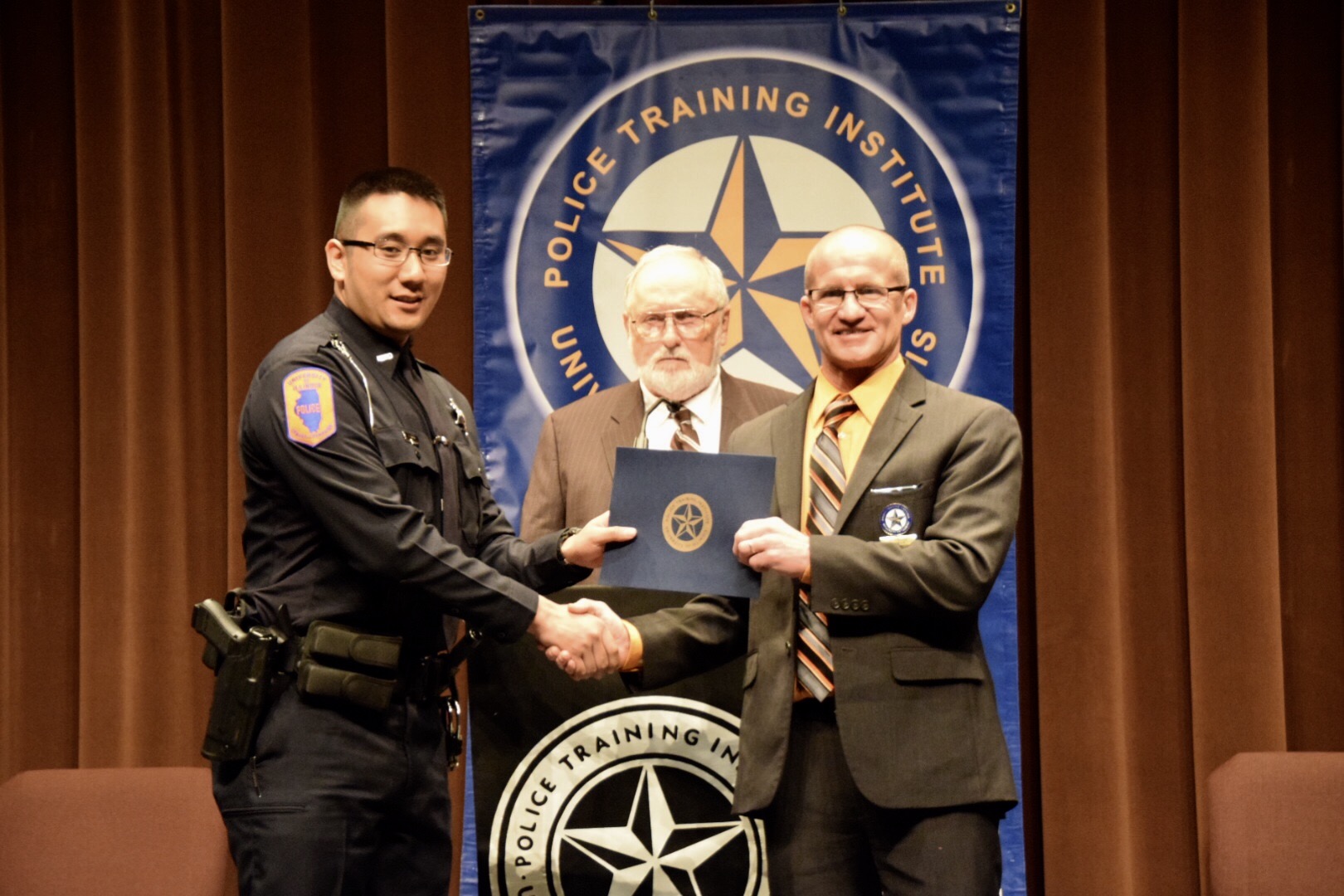 Alex Tran receiving his diploma from Police Training Institute Director Michael Schlosser.