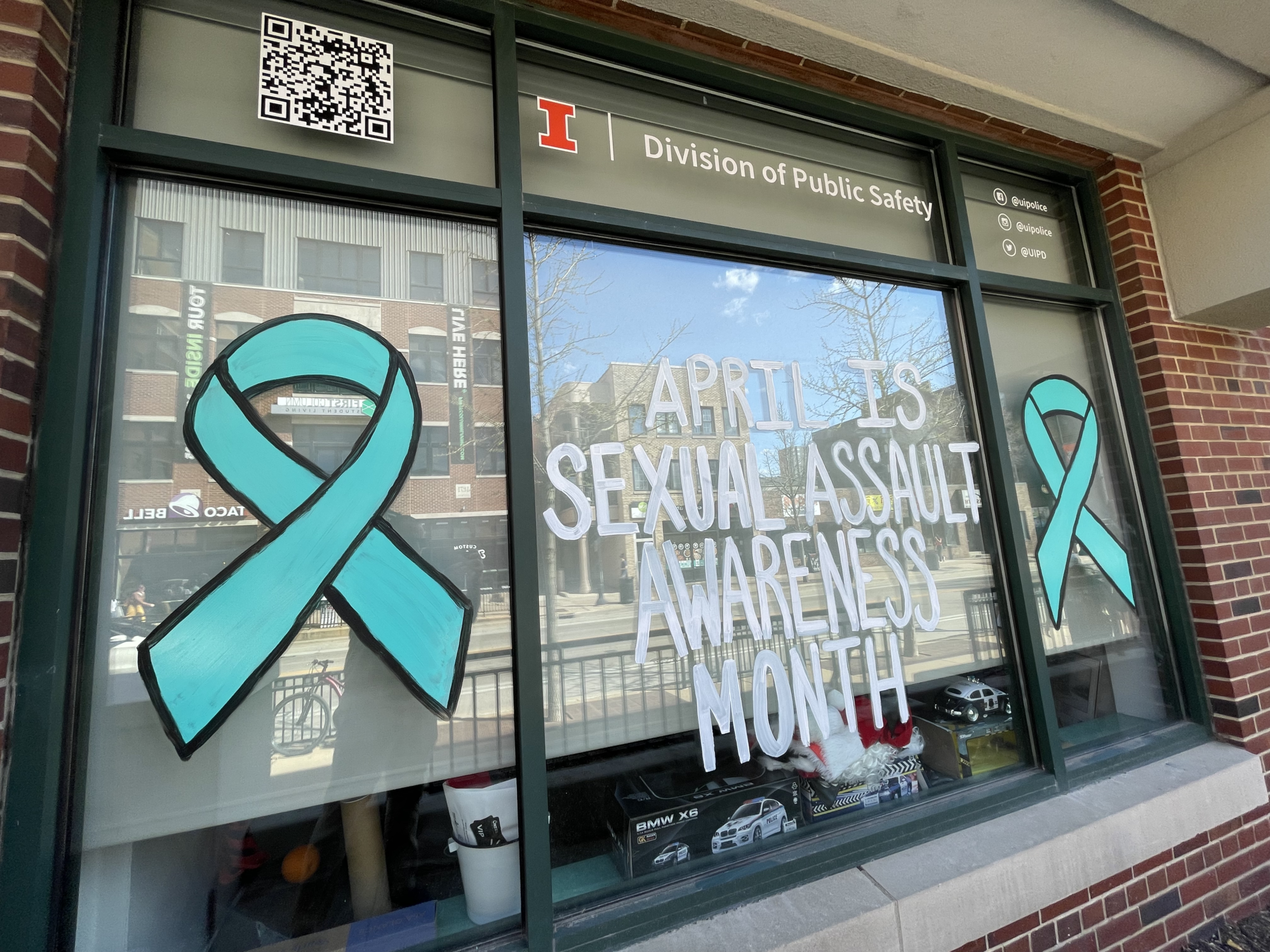 Exterior image of a front office window painted with teal ribbons and the words 